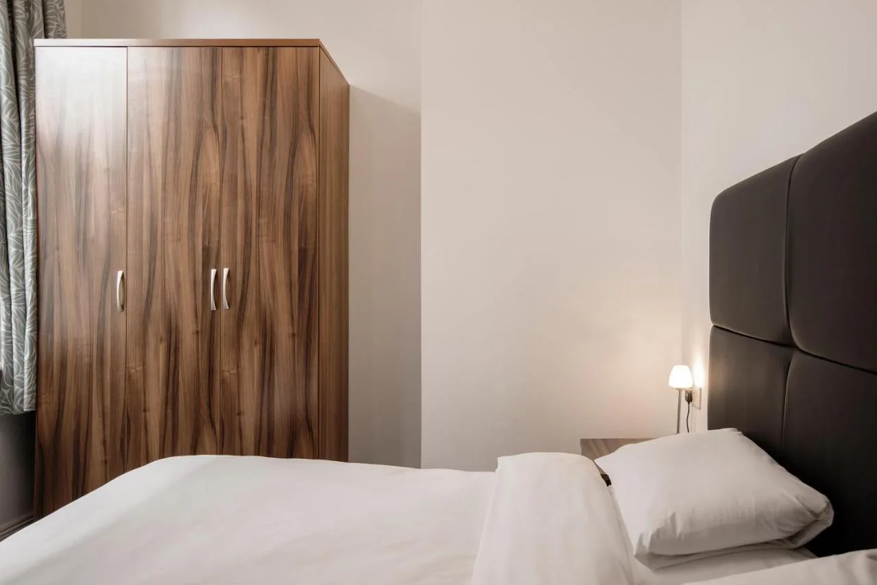a bedroom with a bed and a wooden cabinet at The Castle Collection 14 Cook Street in Liverpool